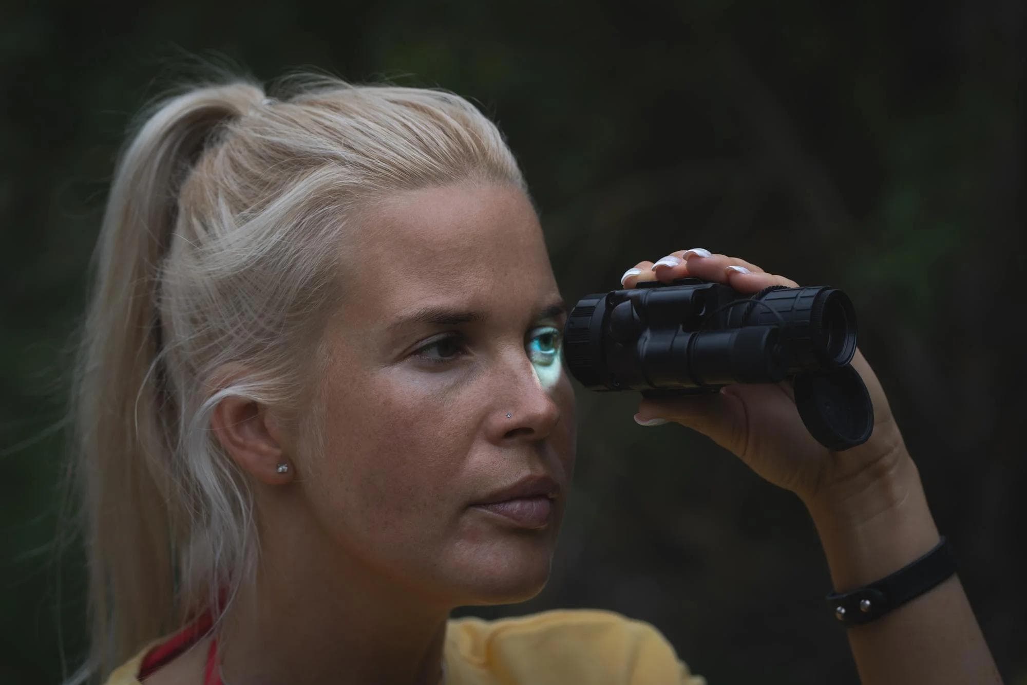 A girl looks through a night vision device at dusk in the forest High quality photo